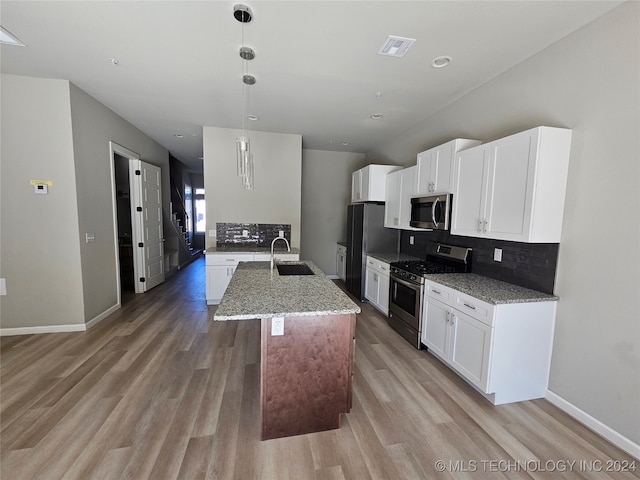 kitchen featuring appliances with stainless steel finishes, sink, hanging light fixtures, white cabinets, and hardwood / wood-style flooring