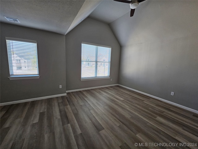 empty room featuring vaulted ceiling, ceiling fan, a textured ceiling, and dark hardwood / wood-style flooring