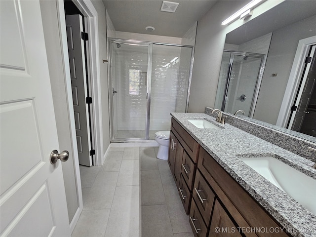 bathroom featuring toilet, a shower with shower door, vanity, and tile patterned flooring