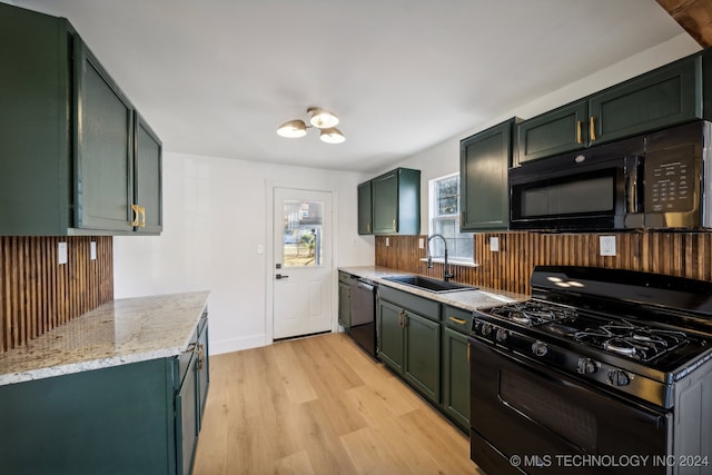 kitchen with sink, black appliances, green cabinets, and light hardwood / wood-style floors