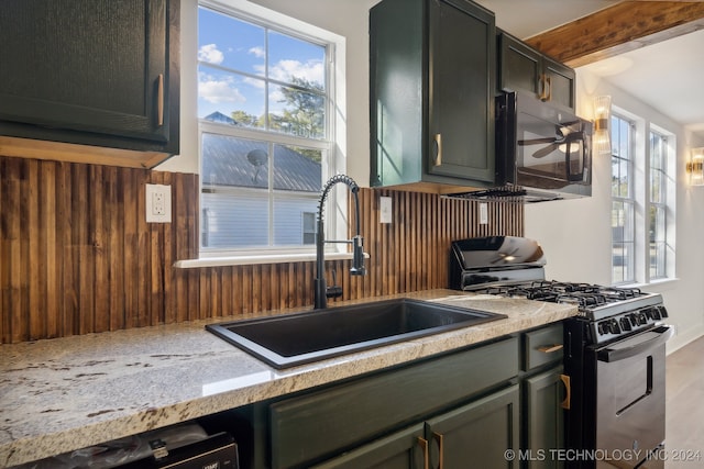 kitchen featuring sink, light stone countertops, a wealth of natural light, and range with gas stovetop