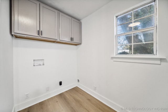 laundry room with light hardwood / wood-style floors, hookup for a washing machine, a healthy amount of sunlight, and cabinets