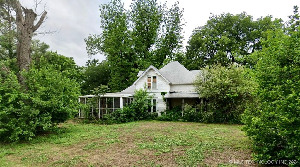 back of property with a yard and a sunroom