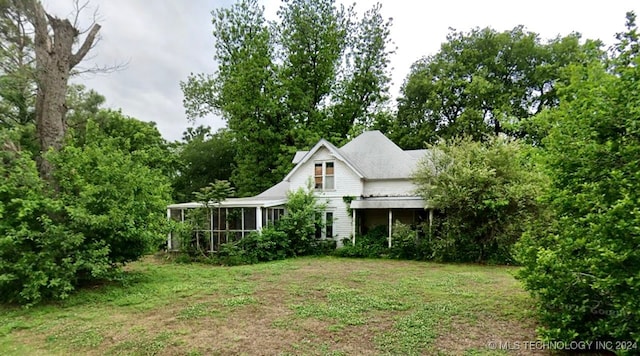 back of property with a yard and a sunroom