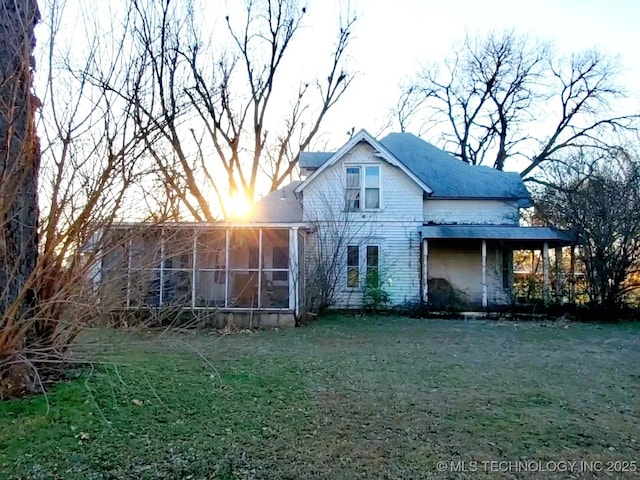 back of house featuring a sunroom and a lawn