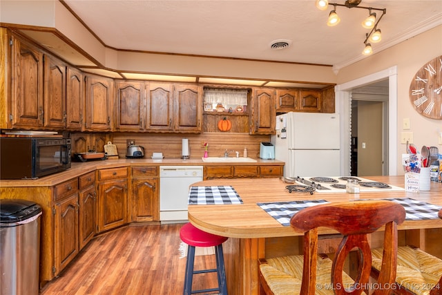 kitchen featuring a textured ceiling, wood-type flooring, crown molding, sink, and white appliances