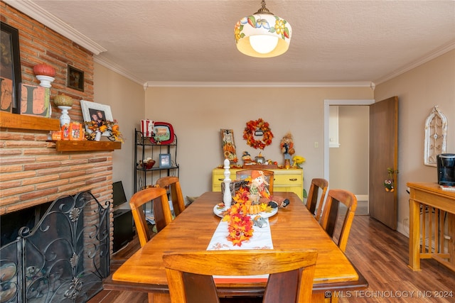 dining area with hardwood / wood-style flooring, ornamental molding, a textured ceiling, and a brick fireplace