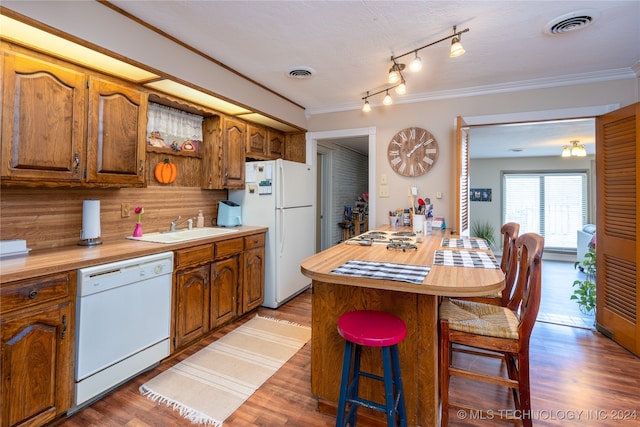 kitchen featuring hardwood / wood-style floors, a kitchen breakfast bar, sink, a center island, and white appliances