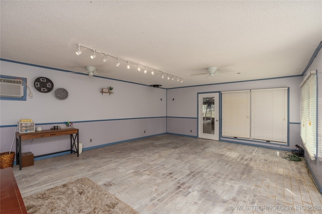 interior space with a textured ceiling, an AC wall unit, light wood-type flooring, and ceiling fan