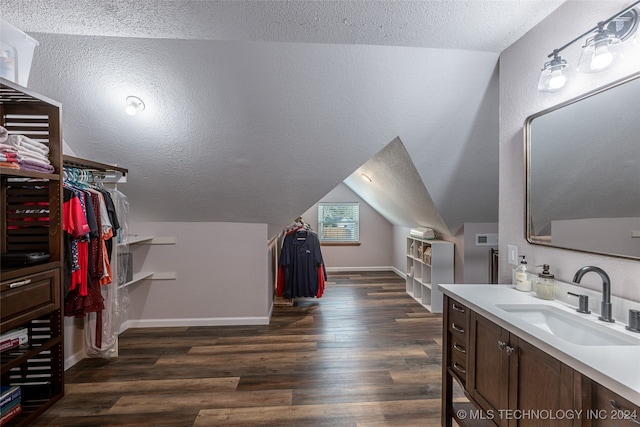 interior space with wood-type flooring, vanity, a textured ceiling, and lofted ceiling