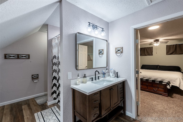 bathroom featuring vaulted ceiling, hardwood / wood-style floors, a textured ceiling, vanity, and ceiling fan