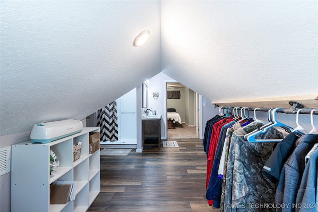 spacious closet with dark wood-type flooring and vaulted ceiling