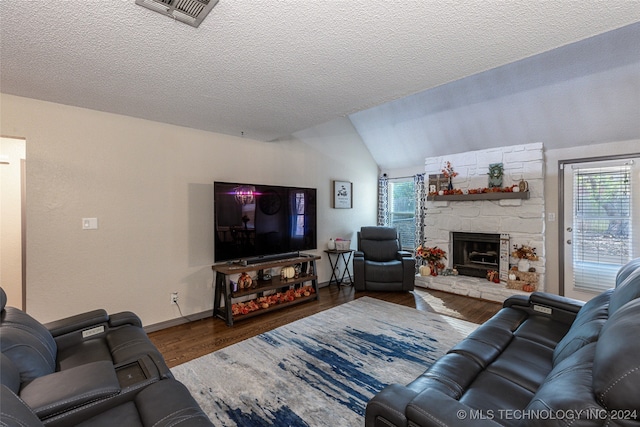 living room featuring a stone fireplace, plenty of natural light, dark wood-type flooring, and lofted ceiling