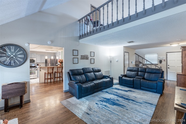 living room with hardwood / wood-style floors, a textured ceiling, and a high ceiling