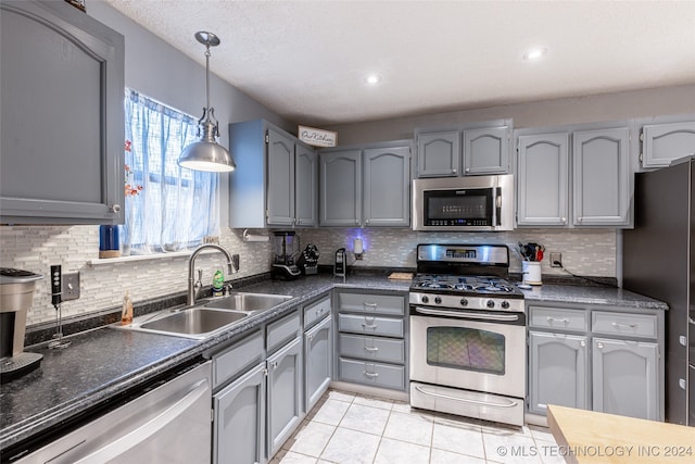 kitchen with sink, appliances with stainless steel finishes, light tile patterned floors, decorative light fixtures, and decorative backsplash