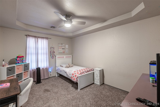 carpeted bedroom with ceiling fan and a raised ceiling