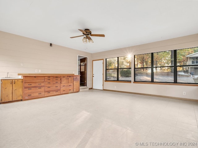 unfurnished living room featuring sink, a healthy amount of sunlight, and ceiling fan