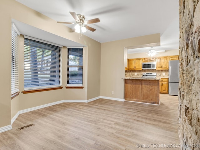 kitchen featuring ceiling fan, stainless steel appliances, tasteful backsplash, and light hardwood / wood-style flooring