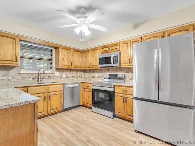 kitchen with backsplash, sink, light wood-type flooring, appliances with stainless steel finishes, and ceiling fan