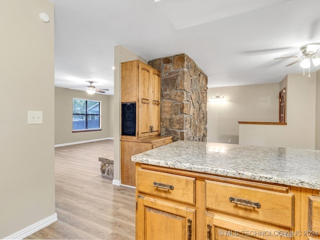 kitchen featuring light stone counters, light wood-type flooring, and ceiling fan