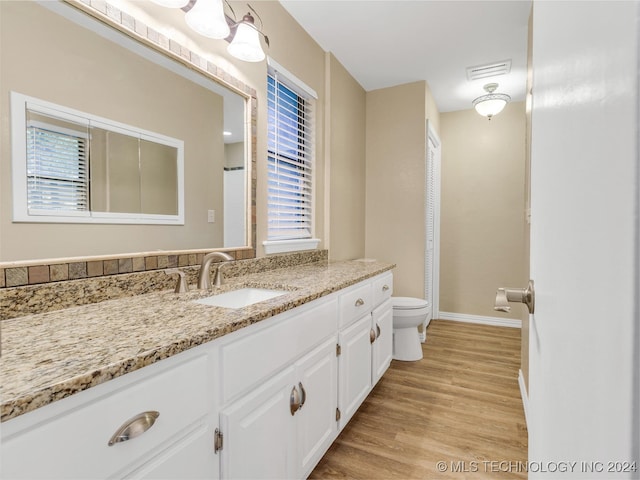 bathroom with toilet, hardwood / wood-style flooring, and vanity