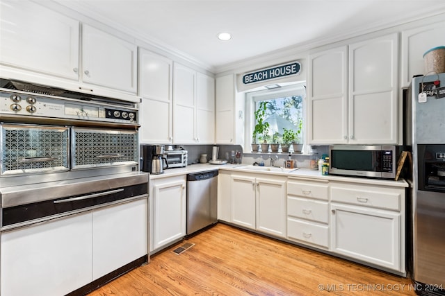 kitchen with white cabinetry, stainless steel appliances, sink, and light wood-type flooring