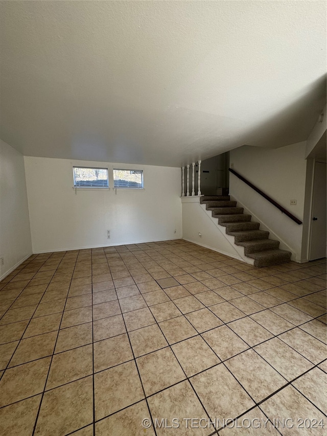 tiled empty room featuring a textured ceiling