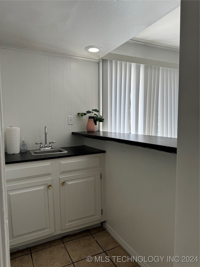 kitchen featuring sink, white cabinetry, a textured ceiling, and light tile patterned floors