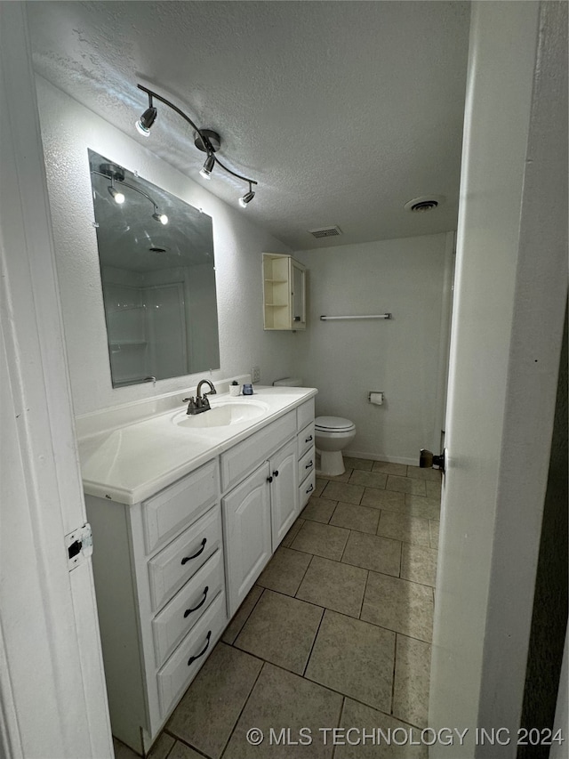 bathroom featuring vanity, a textured ceiling, toilet, and tile patterned flooring