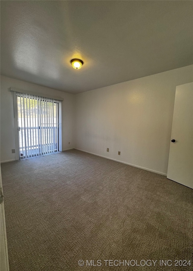 spare room with dark carpet and a textured ceiling