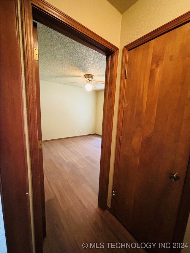 corridor featuring wood-type flooring and a textured ceiling