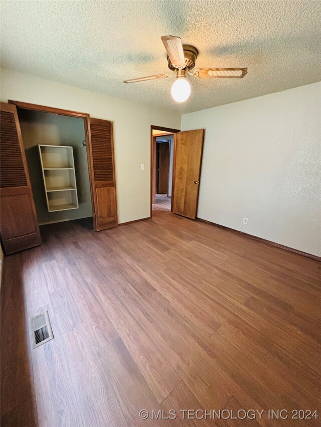 unfurnished bedroom with hardwood / wood-style floors, ceiling fan, and a textured ceiling