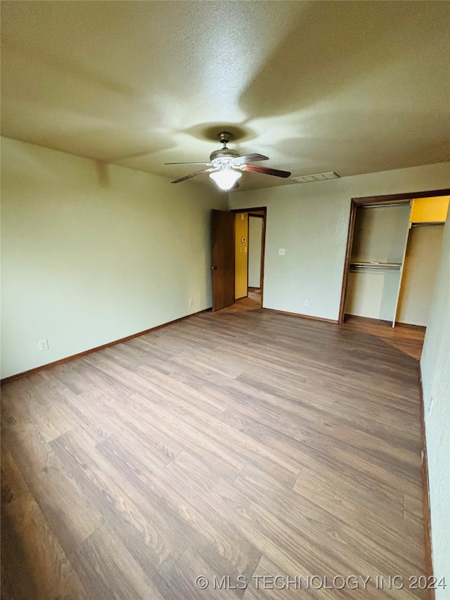 unfurnished bedroom with ceiling fan, a closet, a textured ceiling, and hardwood / wood-style flooring