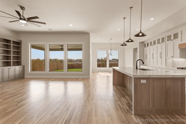 kitchen with white cabinets, a healthy amount of sunlight, sink, and a large island with sink