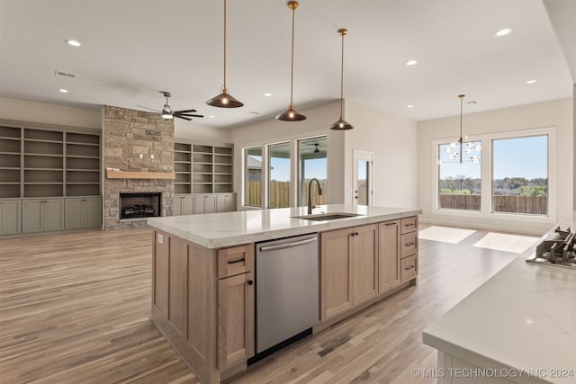 kitchen featuring a stone fireplace, decorative light fixtures, stainless steel dishwasher, and sink