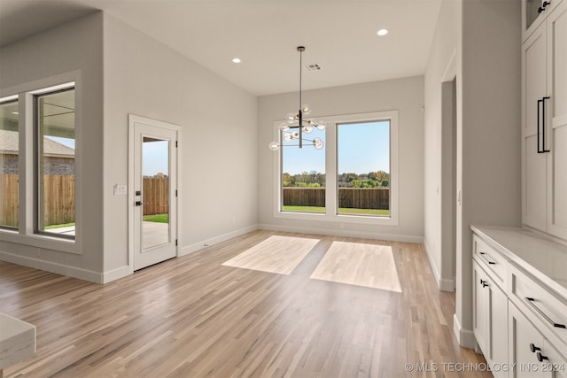 unfurnished dining area with a chandelier and light wood-type flooring