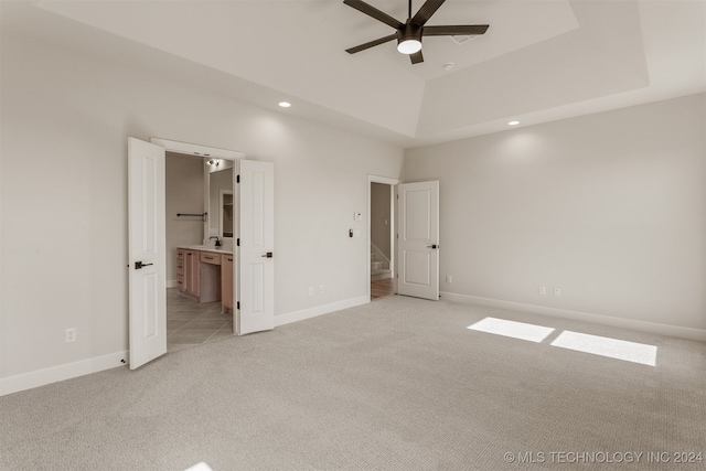 unfurnished bedroom featuring connected bathroom, sink, light carpet, and ceiling fan