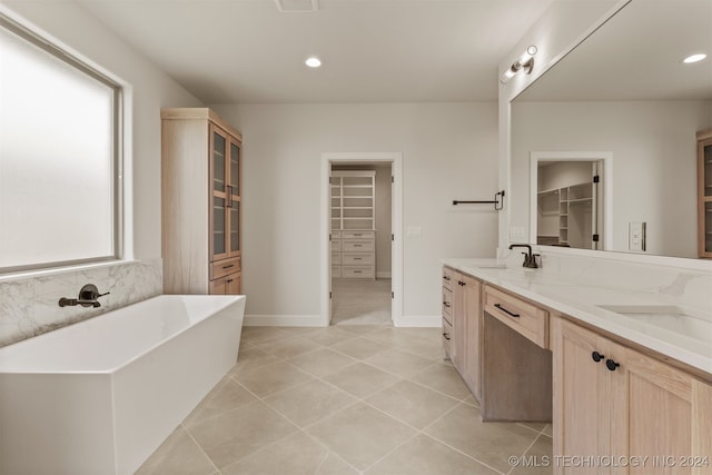 bathroom with a bathing tub, vanity, and tile patterned flooring