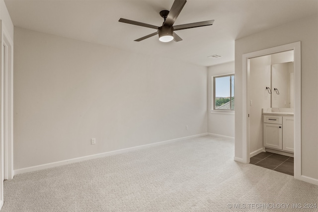 unfurnished bedroom with connected bathroom, dark colored carpet, a closet, and ceiling fan