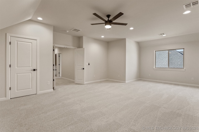 spare room with light colored carpet, vaulted ceiling, and ceiling fan