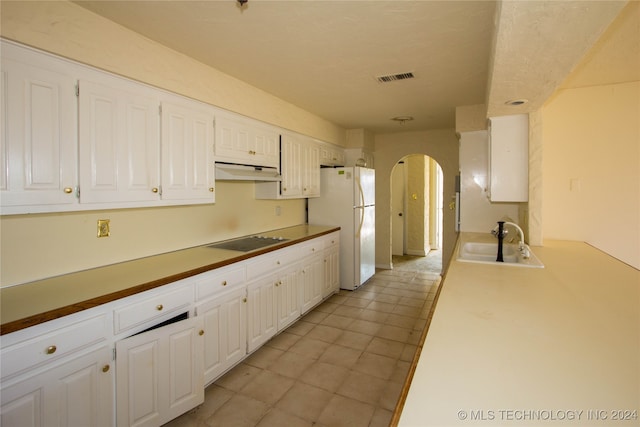 kitchen with black electric cooktop, white cabinetry, sink, and white refrigerator