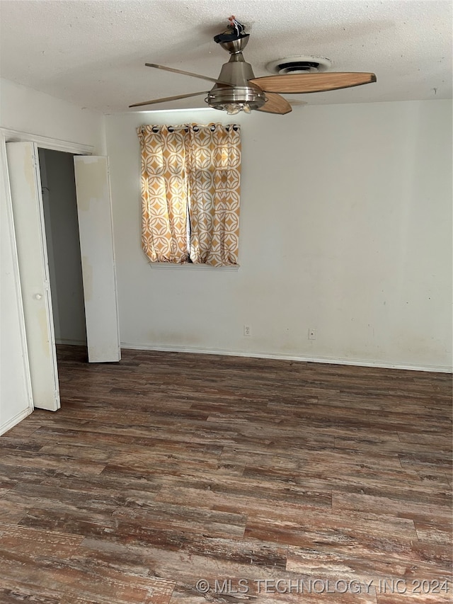 empty room with dark wood-type flooring, a textured ceiling, and ceiling fan