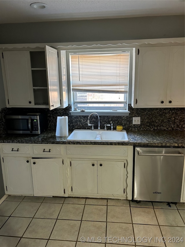 kitchen with appliances with stainless steel finishes, white cabinets, sink, and backsplash