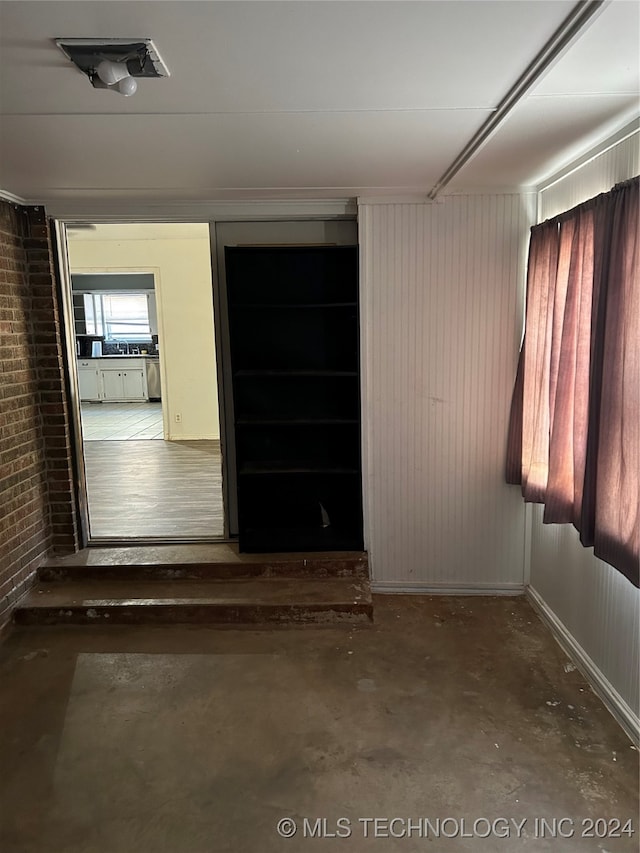 unfurnished room featuring brick wall and concrete flooring