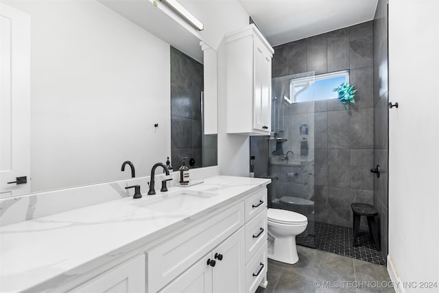 bathroom with vanity, tiled shower, toilet, and tile patterned floors