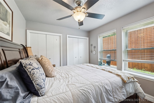 bedroom featuring a textured ceiling, multiple closets, and ceiling fan