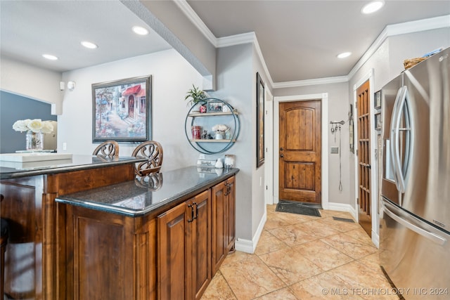 kitchen featuring stainless steel fridge, crown molding, and dark stone countertops