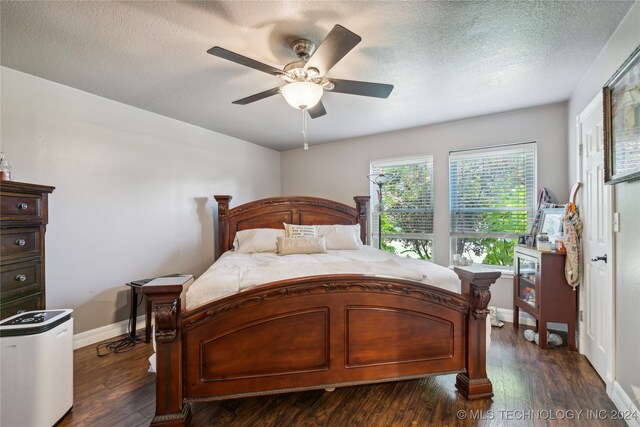 bedroom with dark wood-type flooring, ceiling fan, and a textured ceiling