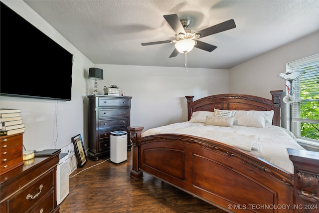 bedroom featuring dark hardwood / wood-style flooring, a textured ceiling, and ceiling fan