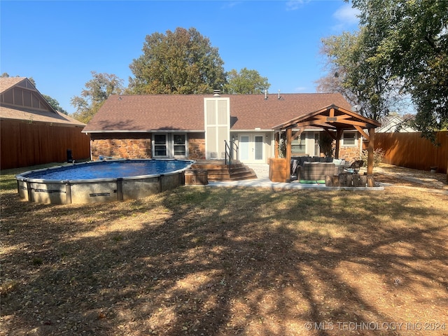 back of property with a yard, a patio, and a fenced in pool